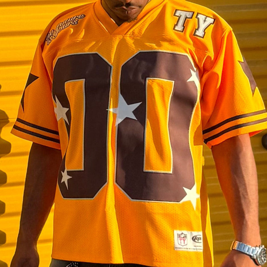 Person wearing a bright orange sports jersey with large brown numbers on a yellow background